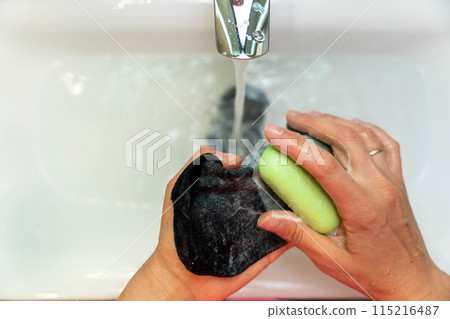 A person hand washing black socks in a bathroom sink with soap A person hand washing black socks in a bathroom sink with soap 115216487