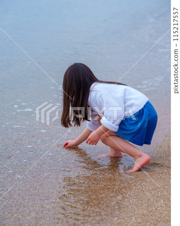 A girl playing on a sandy beach 115217557