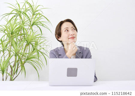 一位女商人在辦公桌前工作，同時在辦公室想像 115218642