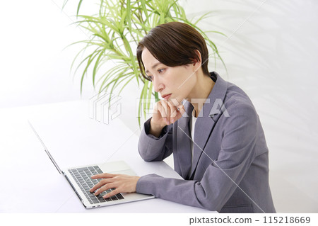 A businesswoman working at her desk while thinking in the office 115218669