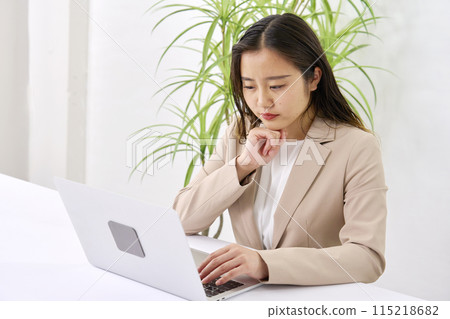 A businesswoman doing desk work in the office while worrying 115218682