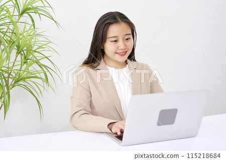 A young businesswoman working at her desk using a computer in the office 115218684