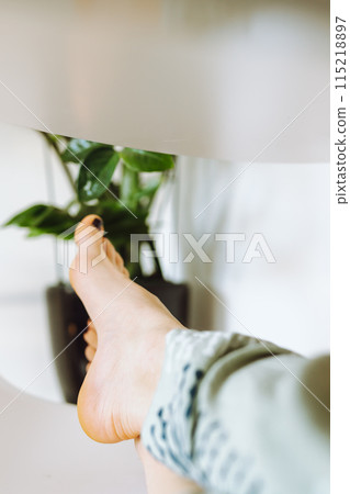 bare feet young woman lying on chair, next to flowerpot 115218897