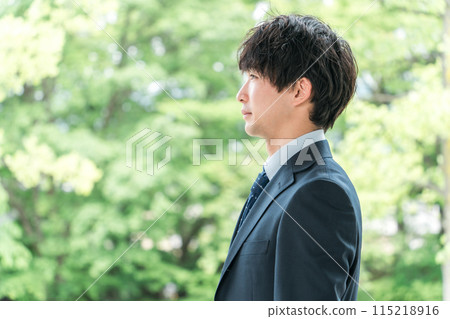 Profile of a young businessman in a suit standing amongst fresh greenery (new employee, job change, job hunting) 115218916