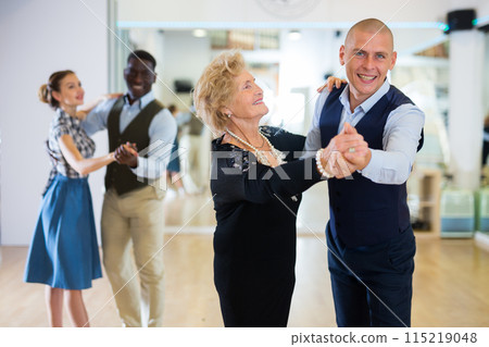 Man and elderly woman performing ballroom dance in dancing room 115219048
