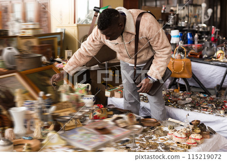 Man chooses antiques at flea market 115219072