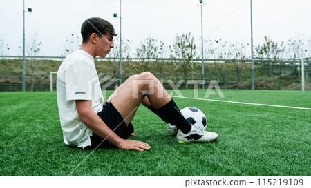 Teenage Soccer Player Sitting on the Side of the Field Breathing Tired 115219109