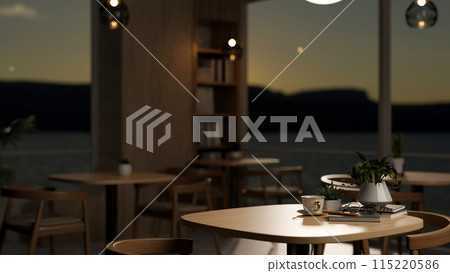 A wooden table with armchairs in a contemporary minimalist restaurant at dusk with a nature view. A wooden table with armchairs in a contemporary minimalist restaurant at dusk with a nature view. 115220586