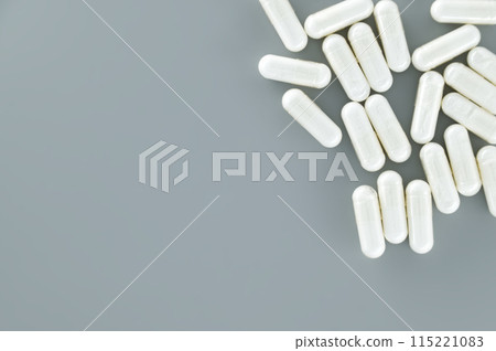 Capsule pills scattered on gray background 115221083