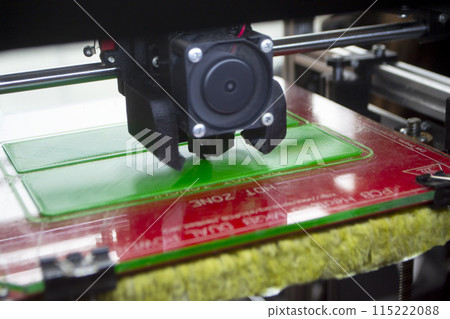 3D printer close up. Working 3D printer close-up. The process of printing on a 3D printer. 3D printer creating an object from molten plastic. 115222088