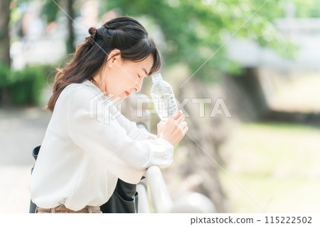 一名亞洲女商人在外出時因脫水和中暑而感到頭暈、頭暈、身體不適。 115222502