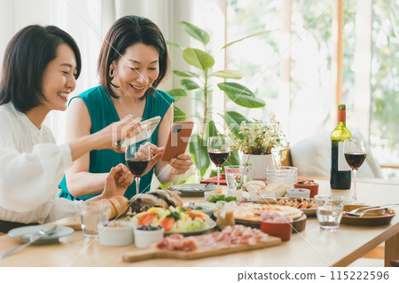 Housewives in their 40s taking photos of food at a girls' get-together at home Housewives in their 40s taking photos of food at a girls' get-together at home 115222596