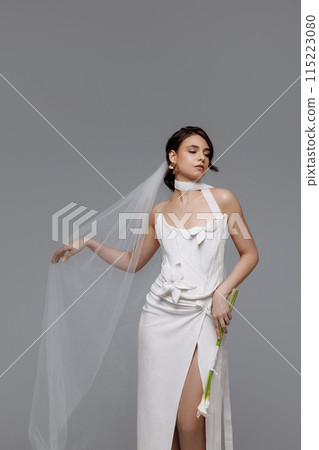 Woman in a white wedding dress on a gray background. 115223080