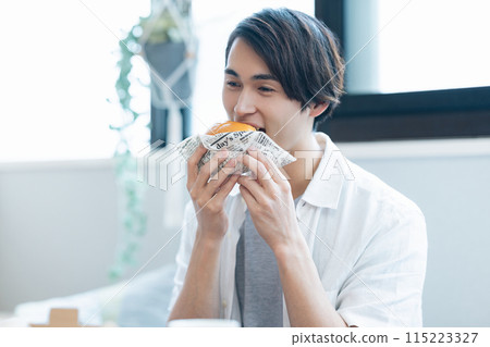 一名男子正在吃外送訂購的食物 一名男子正在吃外送訂購的食物 115223327