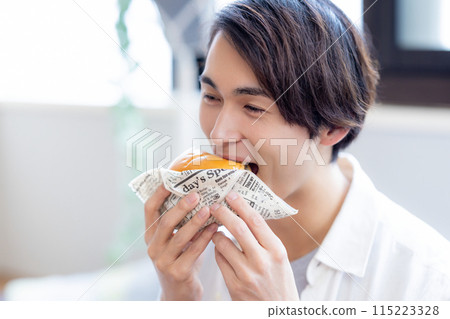 一名男子正在吃外送訂購的食物 一名男子正在吃外送訂購的食物 115223328
