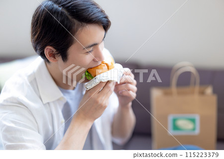 A man eating food he ordered via delivery service A man eating food he ordered via delivery service 115223379