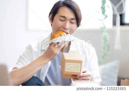 一名男子正在吃外送訂購的食物 115223383