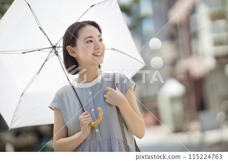 一位年輕女子撐著陽傘穿過城市 一位年輕女子撐著陽傘穿過城市 115224763