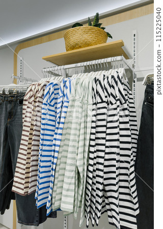 Row of striped shirt and jeans hang on a rack in store Row of striped shirt and jeans hang on a rack in store 115225040