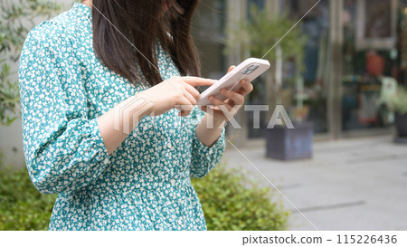 Young woman using a smartphone on the street Young woman using a smartphone on the street 115226436