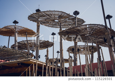 A wooden umbrellas set against the backdrop of a clear blue sky 115226501