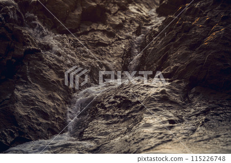 A large rocks surrounded by waves of the ocean A large rocks surrounded by waves of the ocean 115226748