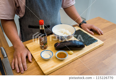 Chef at the kitchen preparing grilled eggplants with garlic 115226770
