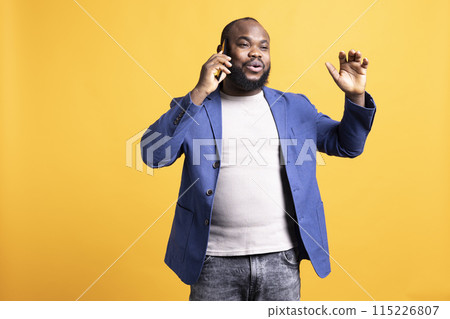 Joyous man with positive emotion, enjoying talking with friends phone call using smartphone, studio background. Happy person with smile on face, receiving good news during telephone call Joyous man with positive emotion, enjoying talking with friends phone call using smartphone, studio background. Happy person with smile on face, receiving good news during telephone call 115226807