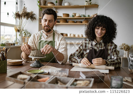 Man and woman sculpting clay together in pottery workshop Man and woman sculpting clay together in pottery workshop 115226823