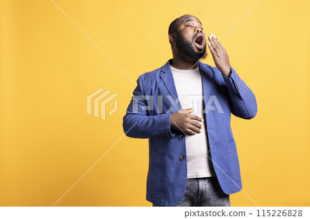 African american man feeling exhausted and yawning, covering his mouth, isolated over studio background. BIPOC person being sleepy during morning, awaken too early, showing sleepiness African american man feeling exhausted and yawning, covering his mouth, isolated over studio background. BIPOC person being sleepy during morning, awaken too early, showing sleepiness 115226828