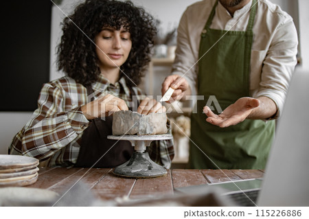 Woman learning pottery with instructor in studio 115226886