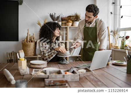 Male and female artisans working together in pottery studio 115226914