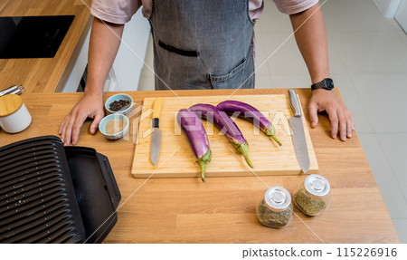 Chef at the kitchen preparing grilled eggplants with garlic 115226916
