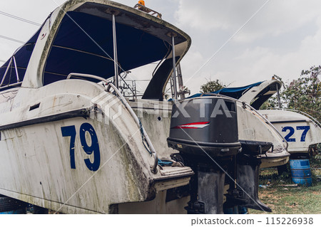Old and rusty motor boats on a landfill surrounded by tropical forest 115226938