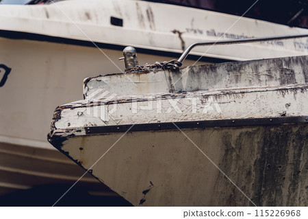 Old and rusty motor boats on a landfill surrounded by tropical forest 115226968