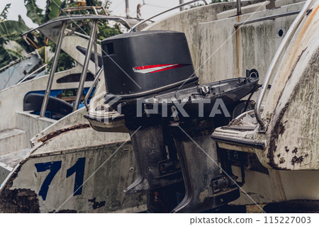 Old and rusty motor boats on a landfill surrounded by tropical forest 115227003