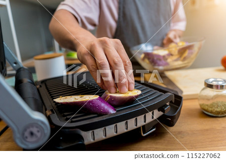 Chef at the kitchen preparing grilled eggplants with garlic Chef at the kitchen preparing grilled eggplants with garlic 115227062