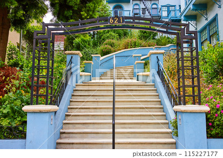 Center of staircase with metal fame going uphill to large blue house with large flowering garden Center of staircase with metal fame going uphill to large blue house with large flowering garden 115227177