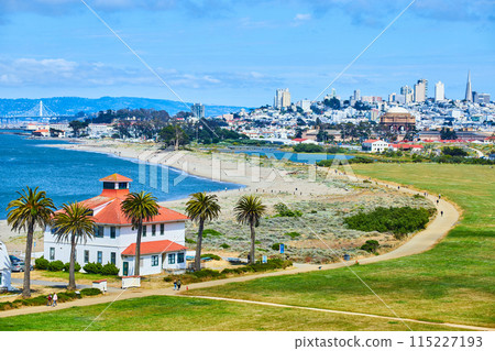 Buildings on edge of San Francisco Bay beach with sandy trail and distant San Francisco skyscrapers 115227193