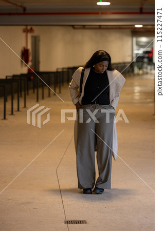Person captured in urban parking garage with neutral tones and reflective industrial elements Person captured in urban parking garage with neutral tones and reflective industrial elements 115227471