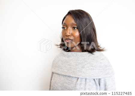 Woman in a fashionable portrait wearing a cozy gray sweater against a minimalist white background Woman in a fashionable portrait wearing a cozy gray sweater against a minimalist white background 115227485