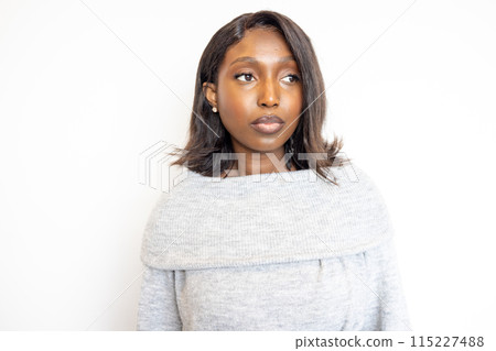 Closeup of a modern woman in a grey sweater, looking thoughtfully with a calm expression Closeup of a modern woman in a grey sweater, looking thoughtfully with a calm expression 115227488