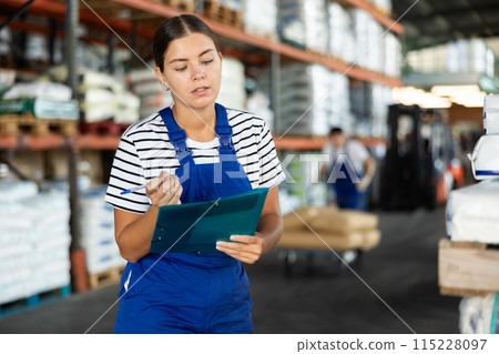 In warehouse of store, girl checks quantity of goods and receipt documents for products In warehouse of store, girl checks quantity of goods and receipt documents for products 115228097