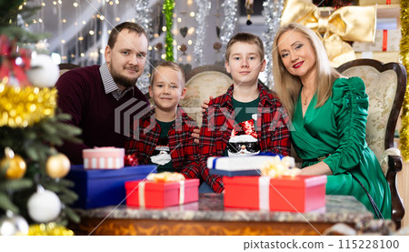 Portrait of happy family with two children celebrating Christmas next to Christmas tree 115228100
