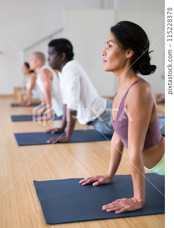 Asian woman performing Upward Facing Dog Pose during group training 115228378