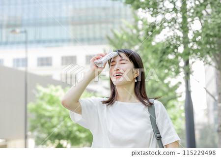 A woman wiping sweat from her forehead with a handkerchief and worrying about the sun 115229498