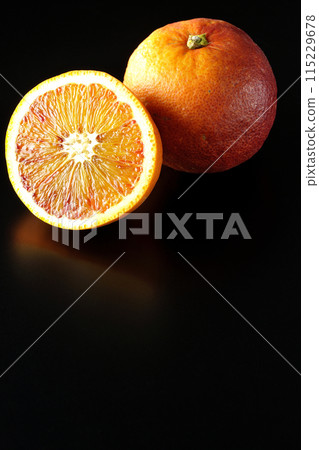 Blood orange photographed against a black background Blood orange photographed against a black background 115229678