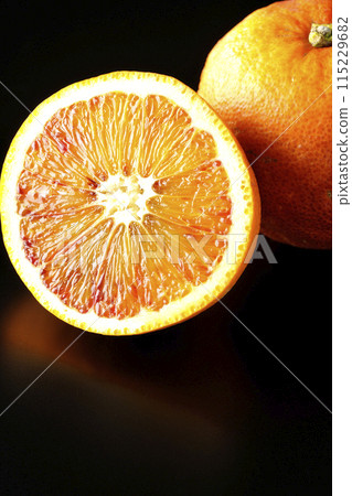Blood orange photographed against a black background 115229682