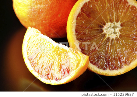 Blood orange photographed against a black background 115229687