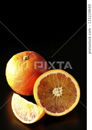 Blood orange photographed against a black background Blood orange photographed against a black background 115229689